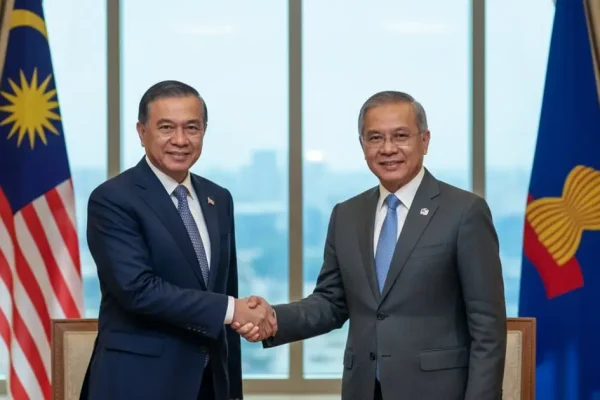 Malaysian official shaking hands with ASEAN diplomat, symbolizing regional cooperation and MM2H program shifts